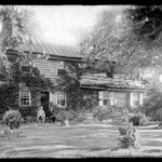 Old home of Job and Elizabeth Collins near Medford. Front view with two seated figures.